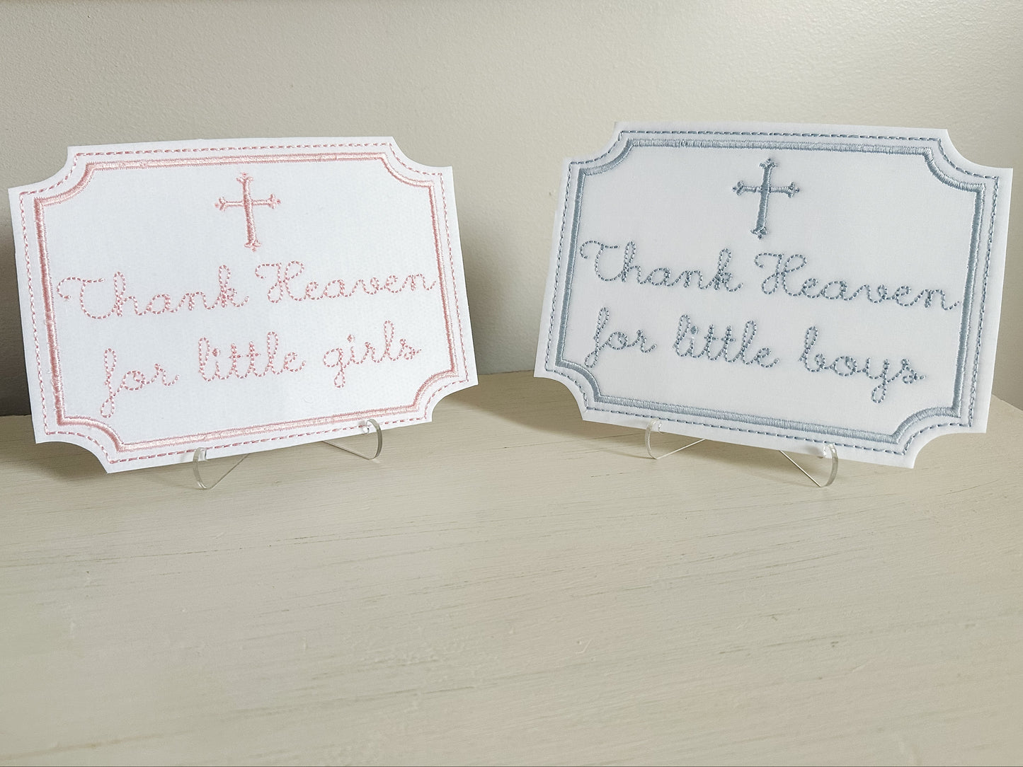 Two signs with text 'Thank Heaven for little girls' and 'Thank Heaven for little boys' on a neutral background.