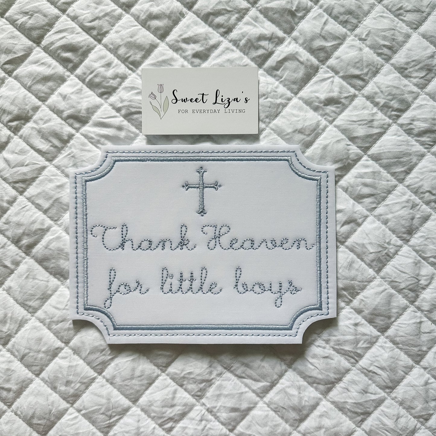 Decorative sign with 'Thank Heaven for little boys' text on a quilted fabric background