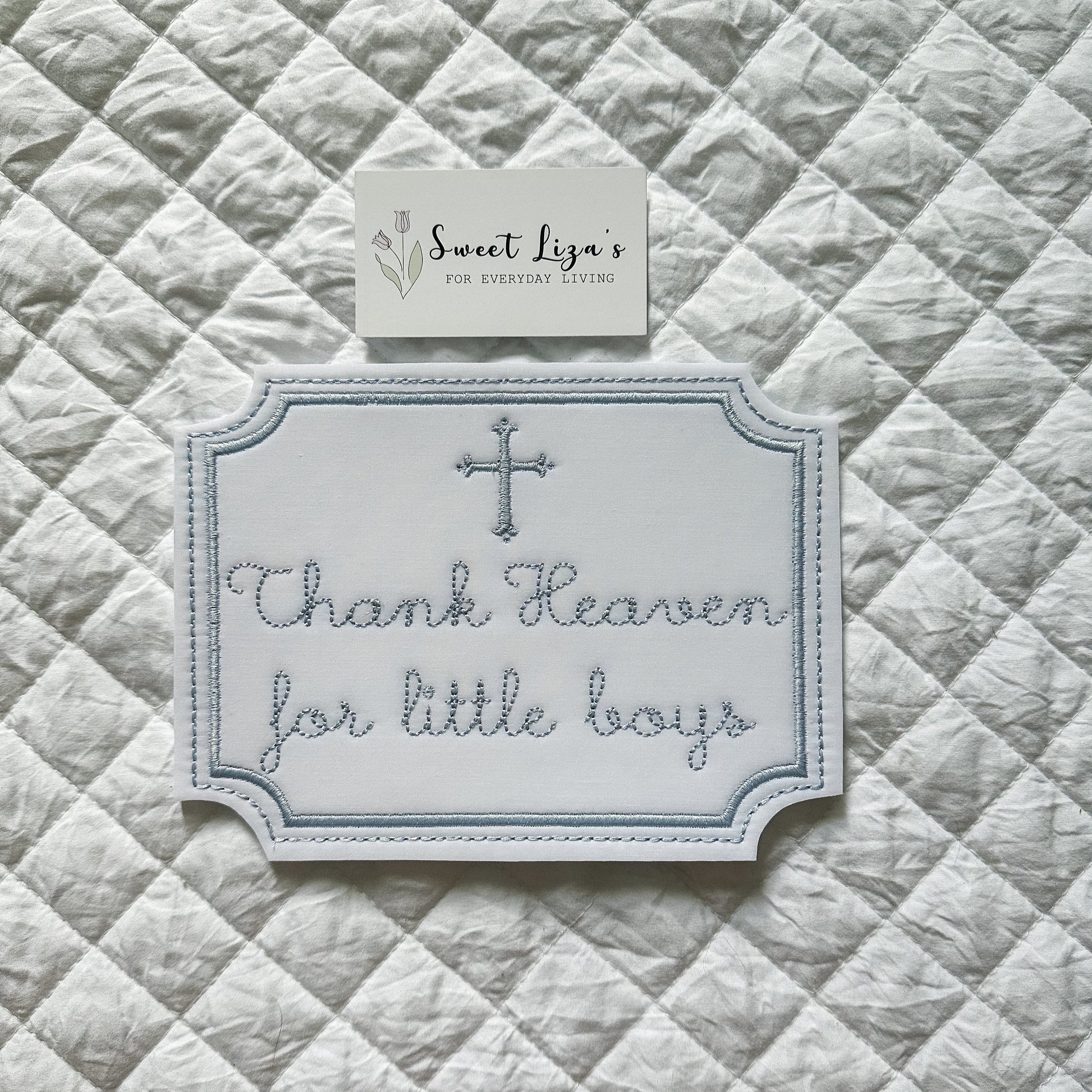 Decorative sign with 'Thank Heaven for little boys' text on a quilted fabric background
