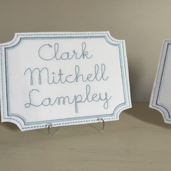 video showing the two previous nameplates on acrylic stands with a neutral background.