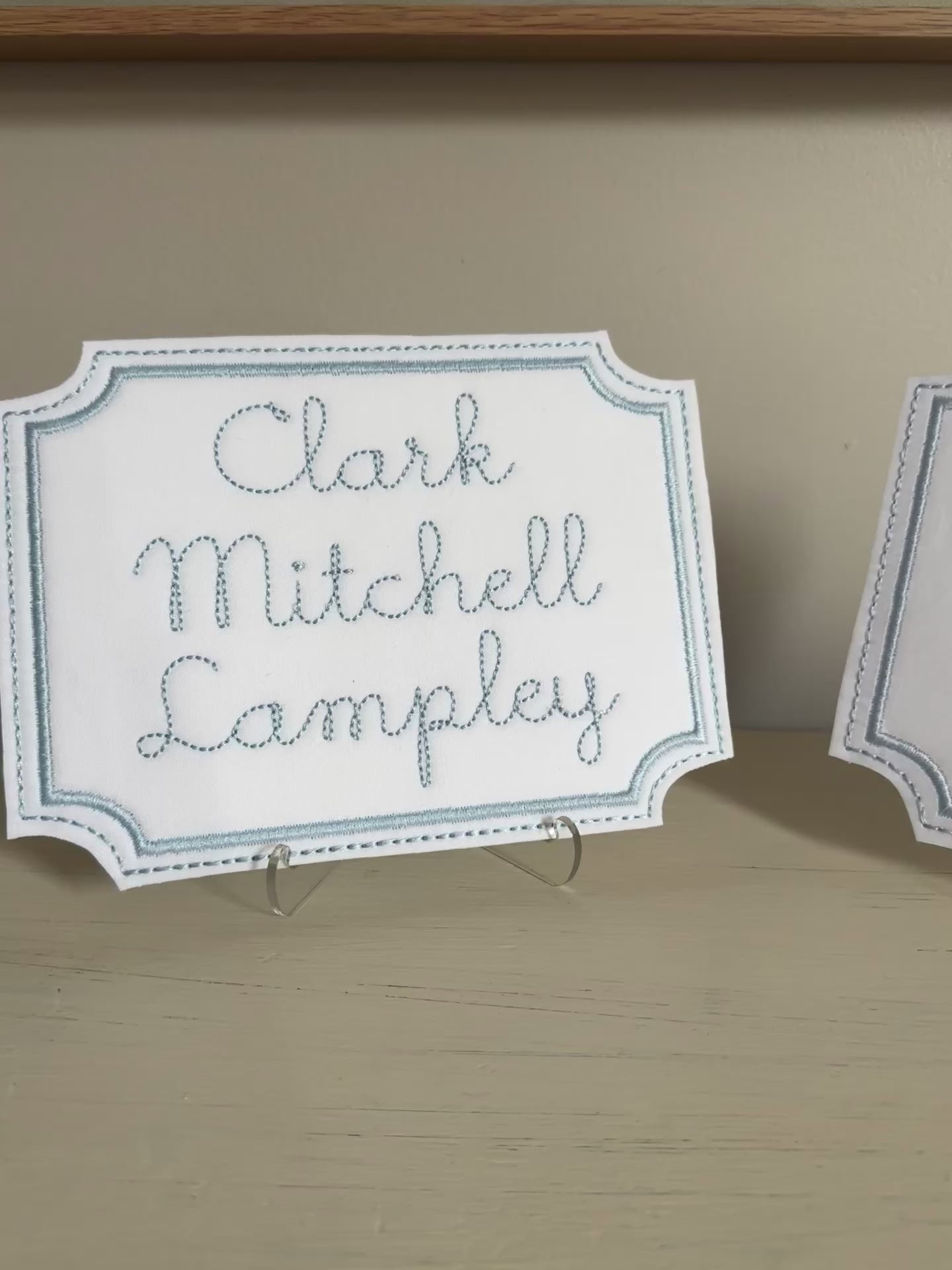 video showing the two previous nameplates on acrylic stands with a neutral background.